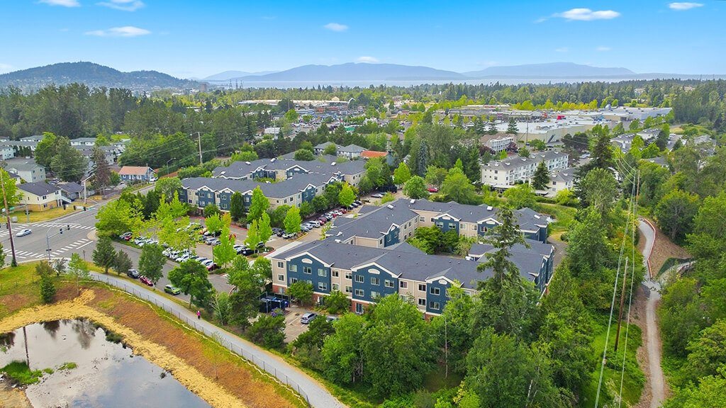 A bird's eye view of a residential area with houses and a pond.